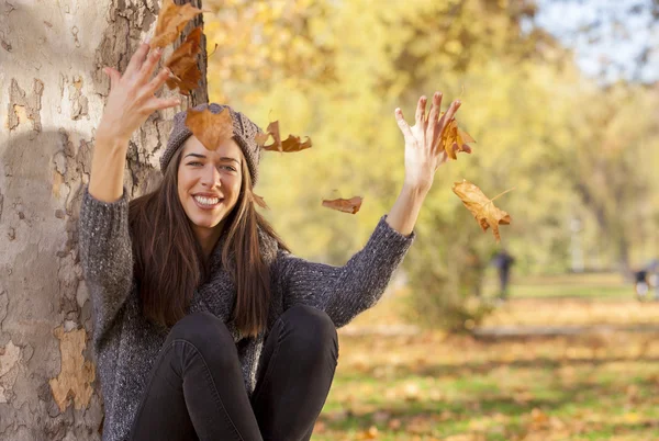 Woman drops up leaves in autumn park — стоковое фото