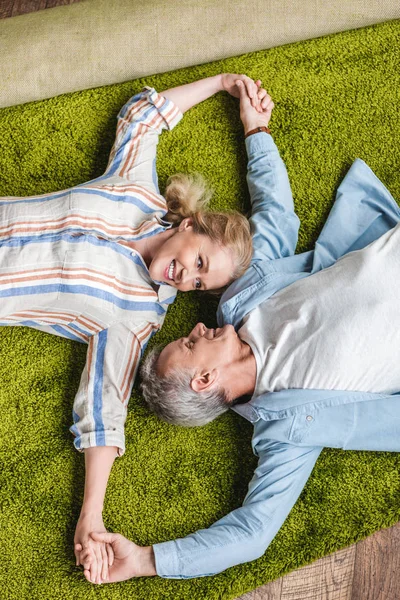 Top View Happy Elderly Couple Lying Together Carpet Holding Hands — стоковое фото