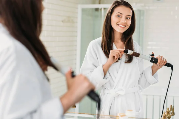 Beautiful Smiling Young Woman Bathrobe Using Hair Curler Mirror Bathroom — стоковое фото